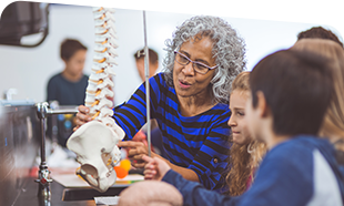 teacher at science table showing skeleton to students