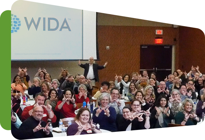 large group of wida staff at tables forming a W with their fingers