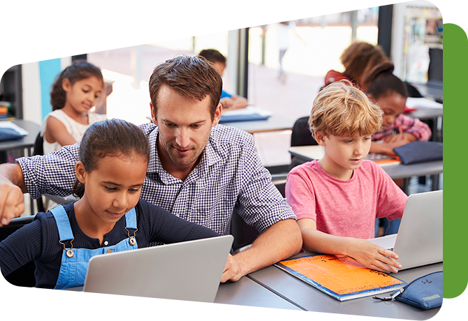 teacher sitting with students at computers