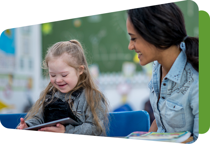 teacher at table with girl with disability holding a tablet