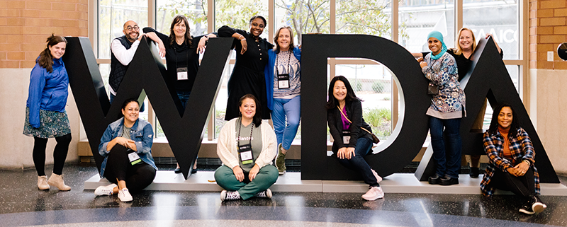 group of conference attendees posing around giant WIDA letters