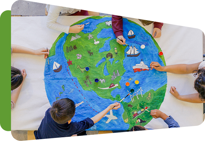 students reaching across large drawing of a globe