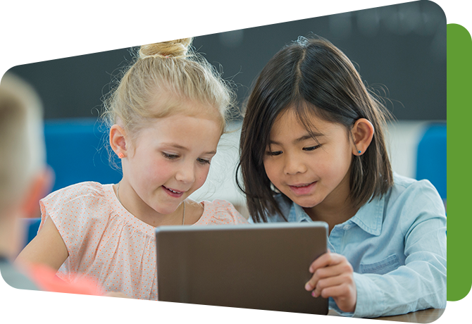 two girls looking at a booklet together at a table