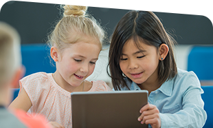 two young students talking and reading from tablet