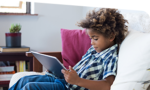 boy reading from tablet on couch