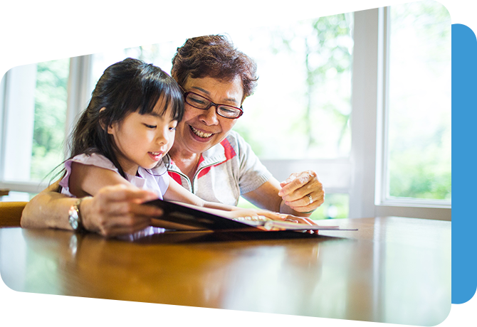 woman and girl reading a book together at a table