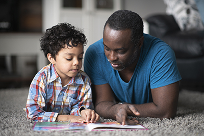 Man and child laying on floor reading