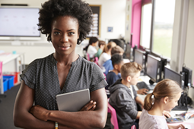 Woman standing in classroom with students on computers