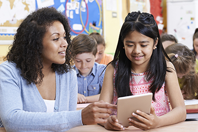 teacher and student looking at tablet in classroom