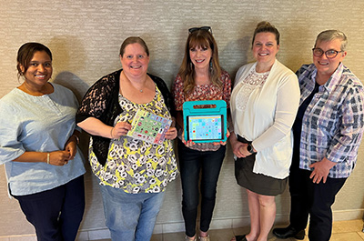 Anne Page with four Advancing ALTELLA staffers holding up AAC devices.