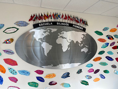 Wall decoration with a map of the world, the words Escuela Bilingüe Pioneer and several country flags