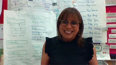 Kindergarten teacher Zahide Marcano stands in front of a classroom board with instructional materials