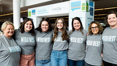 Seven educators wearing matching "WIDA Best" t shirts smile for photo at WIDA Annual Conference