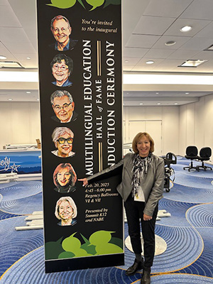 Margo Gottlieb standing next to a sign announcing the Multilingual Education Hall of Fame at NABE’s annual conference.