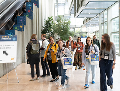 Educators carrying WIDA Annual Conference tote bags walking to their sessions in the Conference Center.