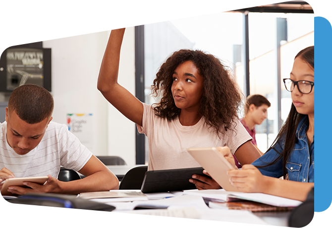 older student raising hand at classroom table with other students