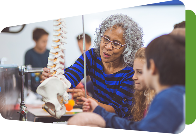 teacher at science lab table showing students a skeleton