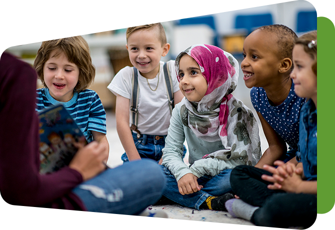 group of young students gathered on the floor around a teacher who is reading to them