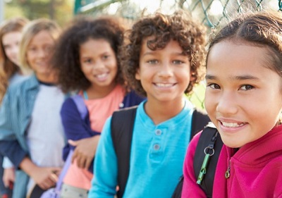 Students smiling while leaning against a chain-link fence